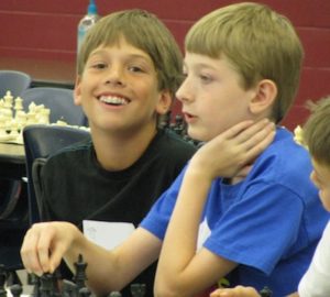 Students playing chess smiling